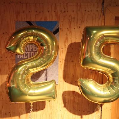 Golden "25" balloons in front of the wooden studio wall