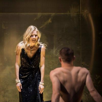 Sienna Miller (Maggie) and Jack O'Connell (Brick) who is leaning with his back to us on a bed in Cat on a Hot Tin Roof 
