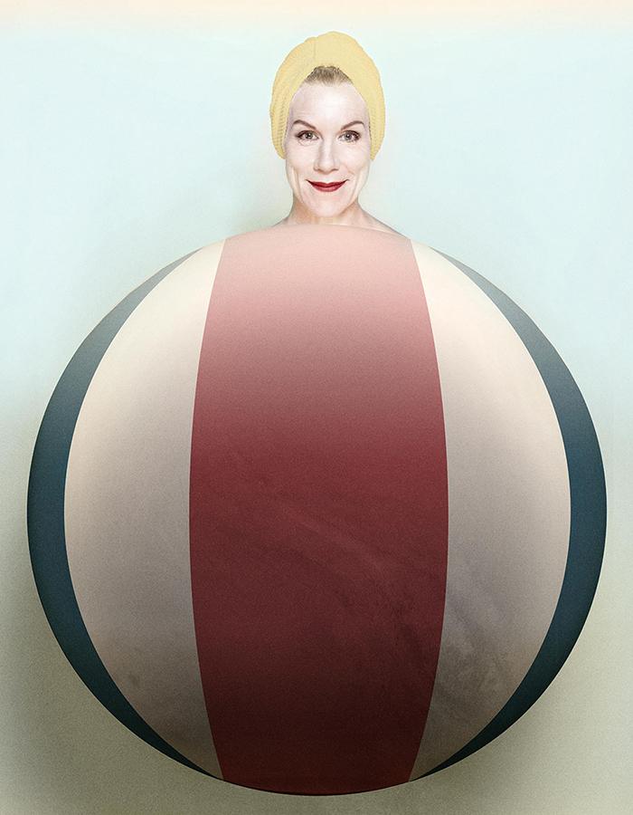 A smiling Juliet Stevenson is superimposed coming out the top of a striped oversized red, white and blue beach ball, almost as if the ball was her body.
