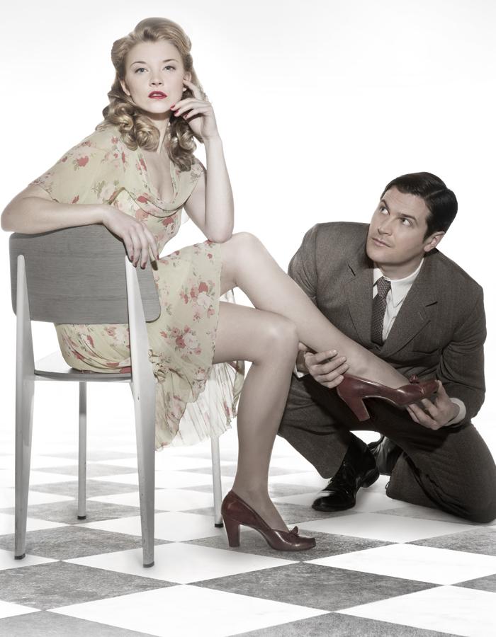 Natalie Dormer sits on a chair as Kieran Bew puts on her shoe