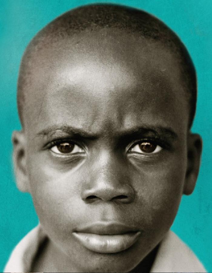 A close up shot of a boy looking straight to the camera with a green background