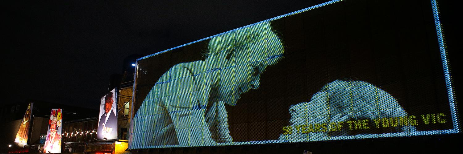 A black and white photo of Vanessa Redgrave in the 1985 Young Vic production of Ghosts is projected outside the the Young Vic building