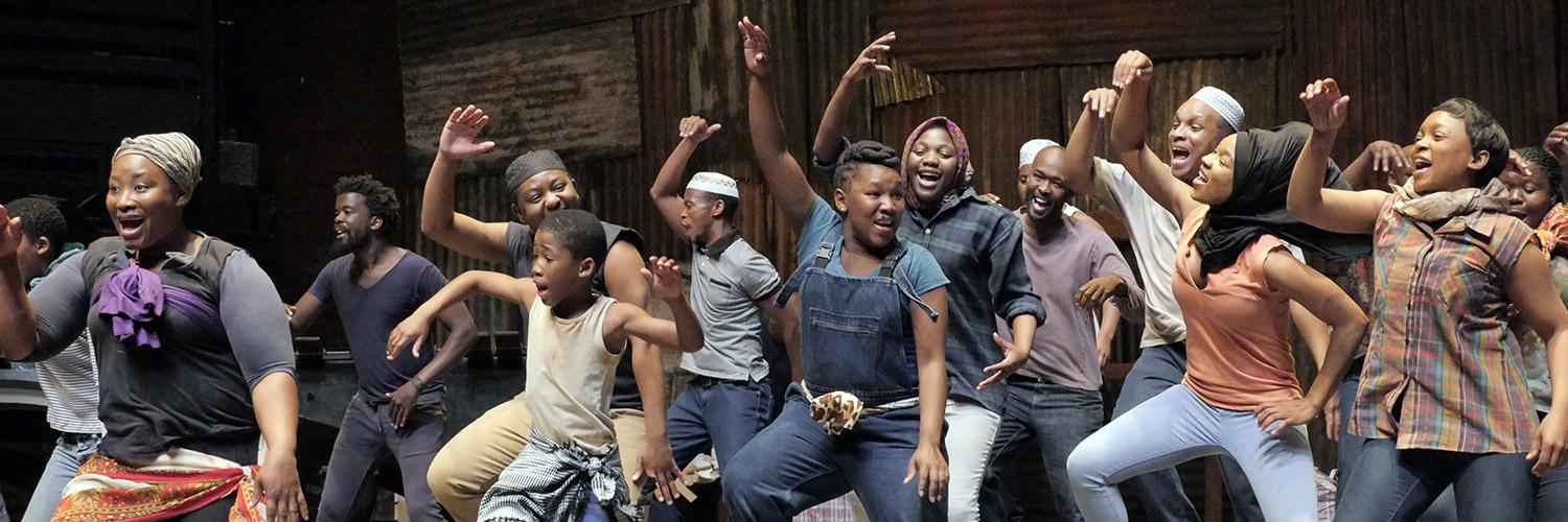 The company of Isango Ensemble's A Man of Good Hope dancing on stage at the Young Vic. Photo by Keith Pattison