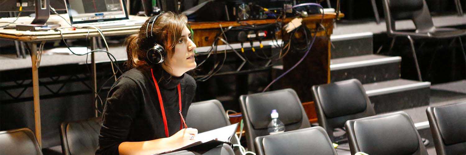 A person sat behind a desk with a lightboard wearing a headset