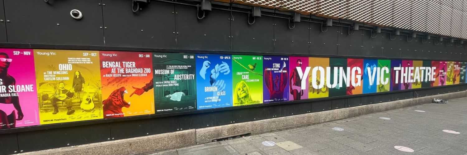 The front of the Young Vic building with a strip of season posters along the wall