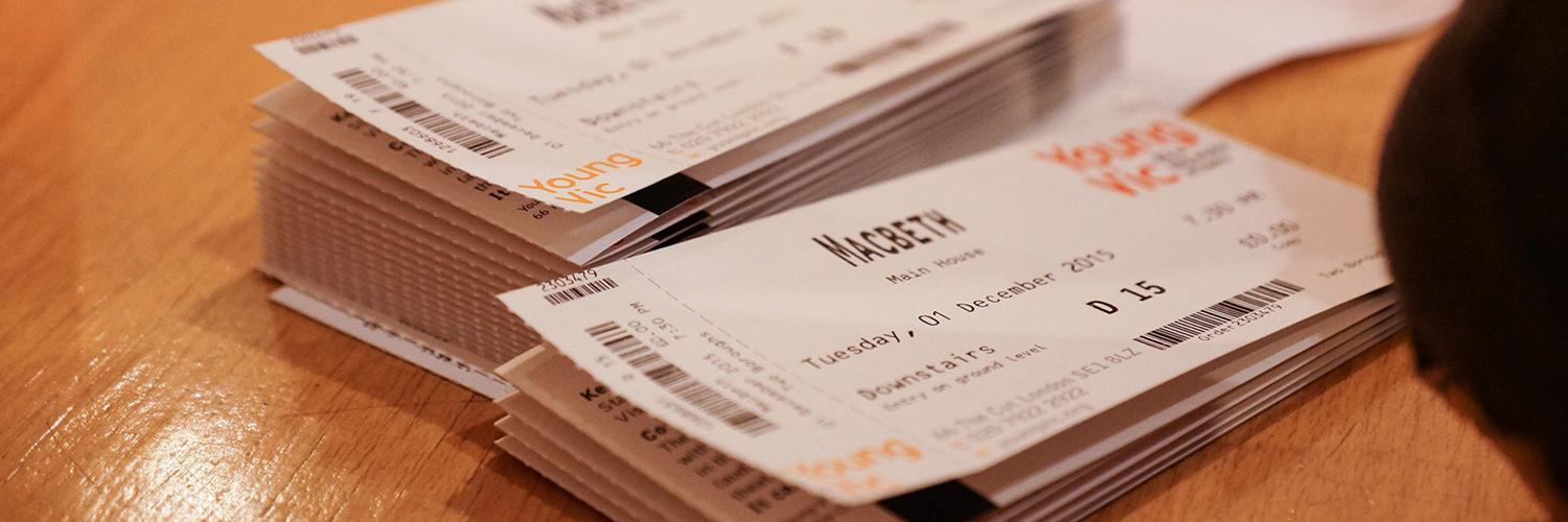 Two stacks of Young Vic tickets sit on a desk. The name of the production and the Young Vic logo is in focus.