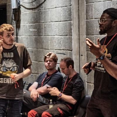 A group of people in a rehearsal room with some standing up and some sitting down