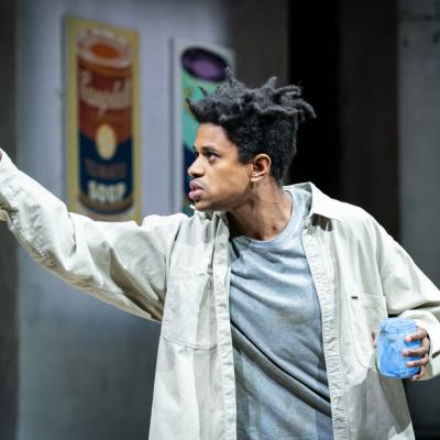  Jeremy Pope in The Collaboration (c) Marc Brenner. Basquiat holding a pot of blue paint whilst painting on a "canvas" which isn't visible to the audience