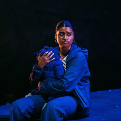 Woman sat on the floor, holding a baby, bathed in blue light