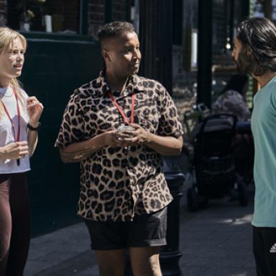 Three people standing on a street talking to one another