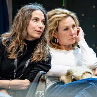 Two actresses sitting on the chairs in the rehearsal room looking away from the camera