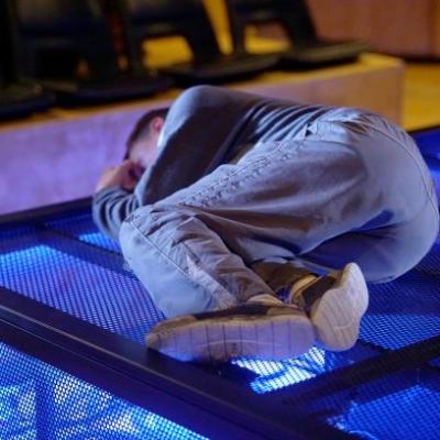 Ivan is curled up in a ball on the stage floor. Photo by Anthony Lee at the Young Vic.