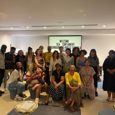 A group of people, neighbourhood voices 2022 company, stood in front of a cinema style sign saying "Neighbourhood Voices"