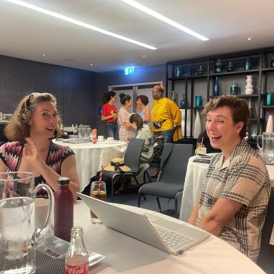 Two women smiling, sat at a table.