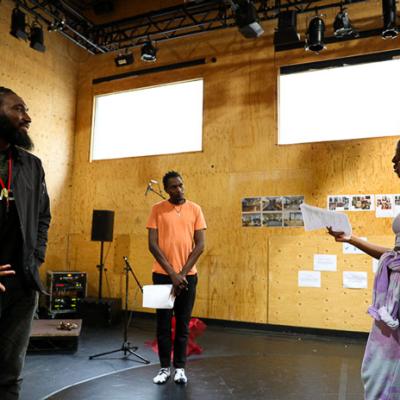 Actress Danielle Kassaraté, Actor John Rwothomach, Director Daniel Bailey, Stage Manager Sylvia Darkwa-Ohemeng, Design Consultant QianEr Jin, and Deputy Stage Manager Emily Behague are standing in a circle looking engaged.