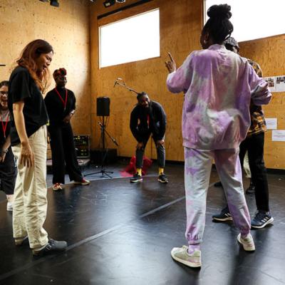 Actress Danielle Kassaraté, Actor John Rwothomach, Director Daniel Bailey, Stage Manager Sylvia Darkwa-Ohemeng, Design Consultant QianEr Jin, and Deputy Stage Manager Emily Behague are standing in a circle looking engaged.