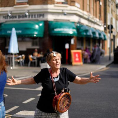 A person standing on a street, wearing a handbag designed to look like a clock around their body