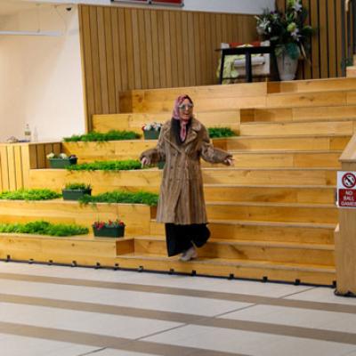 A person walking down a set of wooden stairs, decorated with green plants