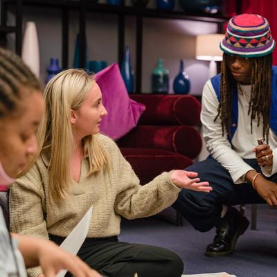 A group of people sitting on the floor, talking to each other