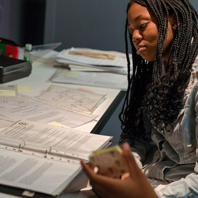 Two people sitting at a table, looking at pieces of paper and talking to each other