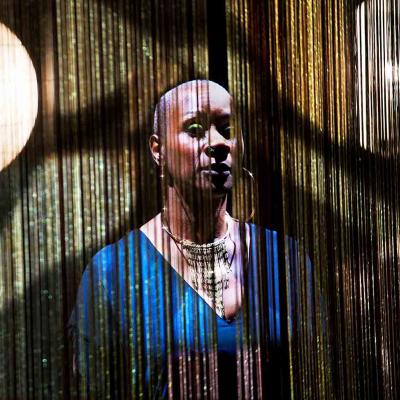 Josette Bushell-Mingo in Nina with beautiful fringed curtains and show lights behind her. Photo by Simon Annand