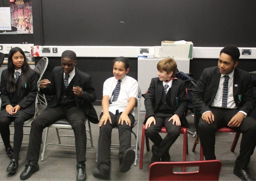 5 seated pupils in their uniforms, talking