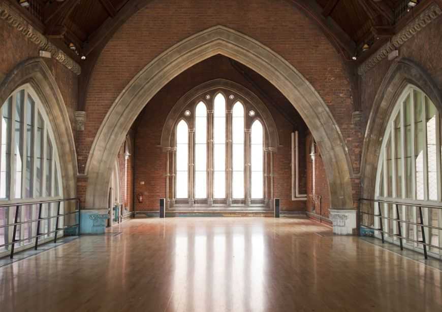 An empty rehearsal space at Jackson's Lane, with vaulted ceiling and large feature windows.