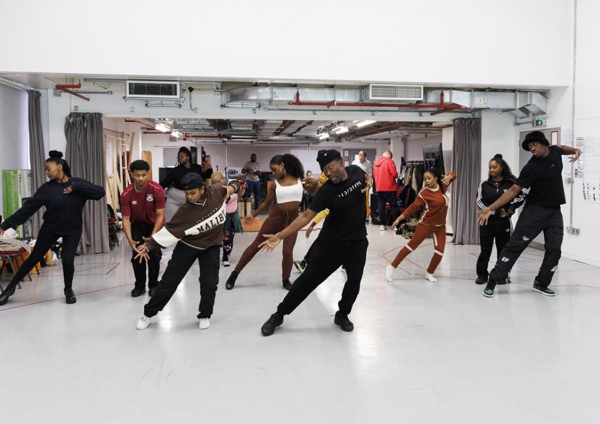 The cast of Mandela in rehearsal dancing with the right hand pointing down