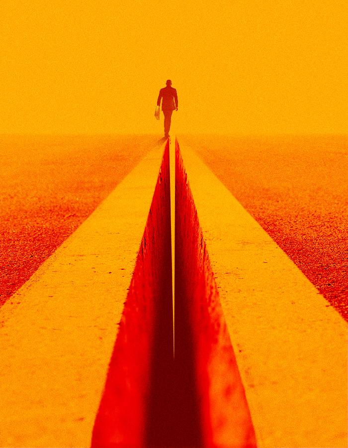 Death of a Salesman poster image. A smartly dressed man in a suit is seen from behind walking into the distance. The ground has a large and deep crack running through it and he is walking along the left side of the edge of the gap.