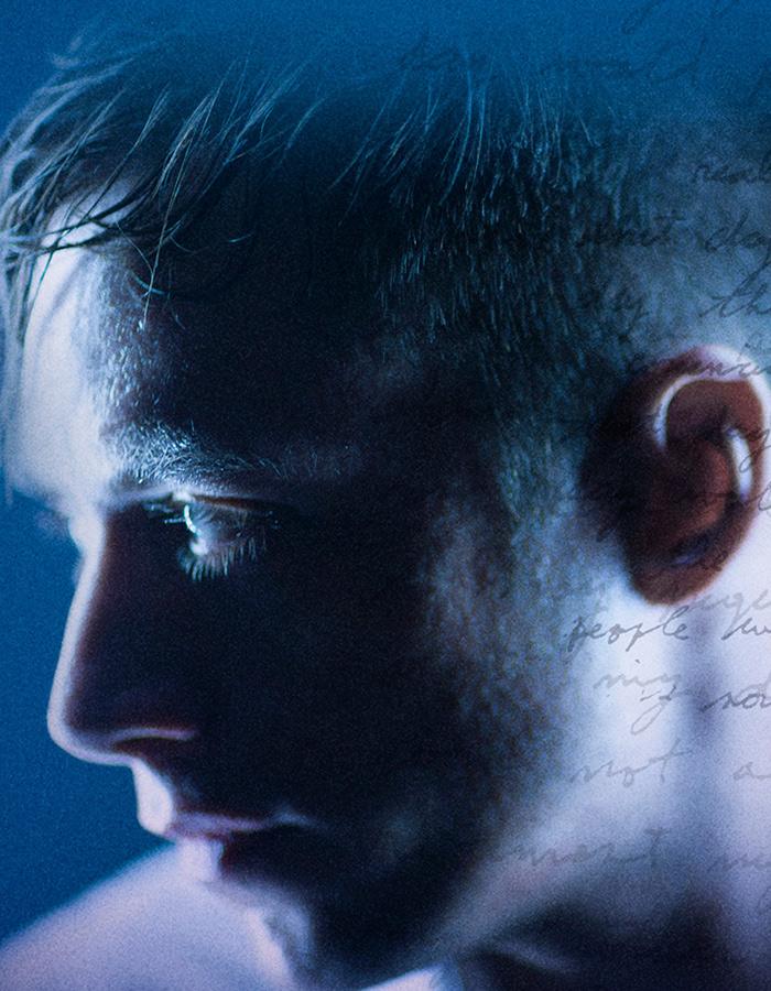 Profile of a man's face with writing superimposed across the image against a blue background