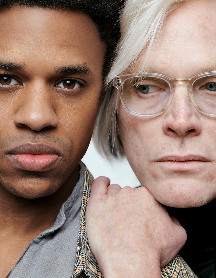 Close up of a black man and a white man wearing glasses, the white man has his hand on the black man's shoulder