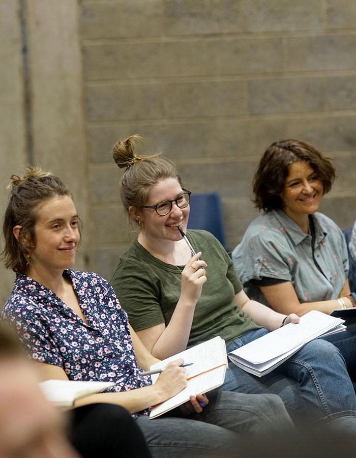 A photo of people sitting with notepads who are all smiling and paying attention