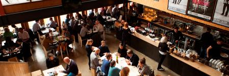 A busy photo of the The Cut Bar in the daytime with people seated at tables and waiting at the bar