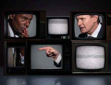 6 1960s TVs stacked on top of each other. David Harewood is split across 2 TVs and Charles Edwards in pointng at him, also split across 2 TVs. There is white noise on the other screens 