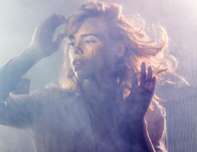 Billie Piper stands behind a misty pane of glass looking wistfully into the distance
