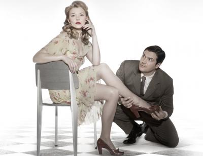 Natalie Dormer sits on a chair as Kieran Bew puts on her shoe