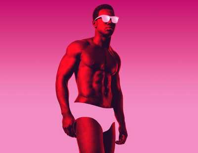 A Black man wearing sunglasses and underwear stands in front of a bright pink background. 