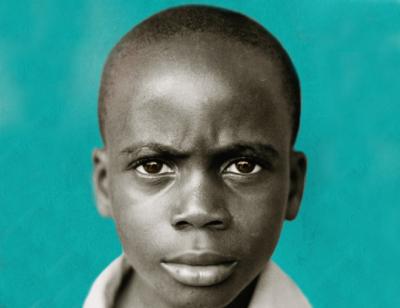 A close up shot of a boy looking straight to the camera with a green background