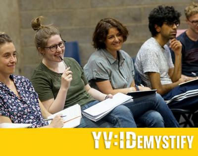 A photo of people sitting with notepads who are all smiling and paying attention